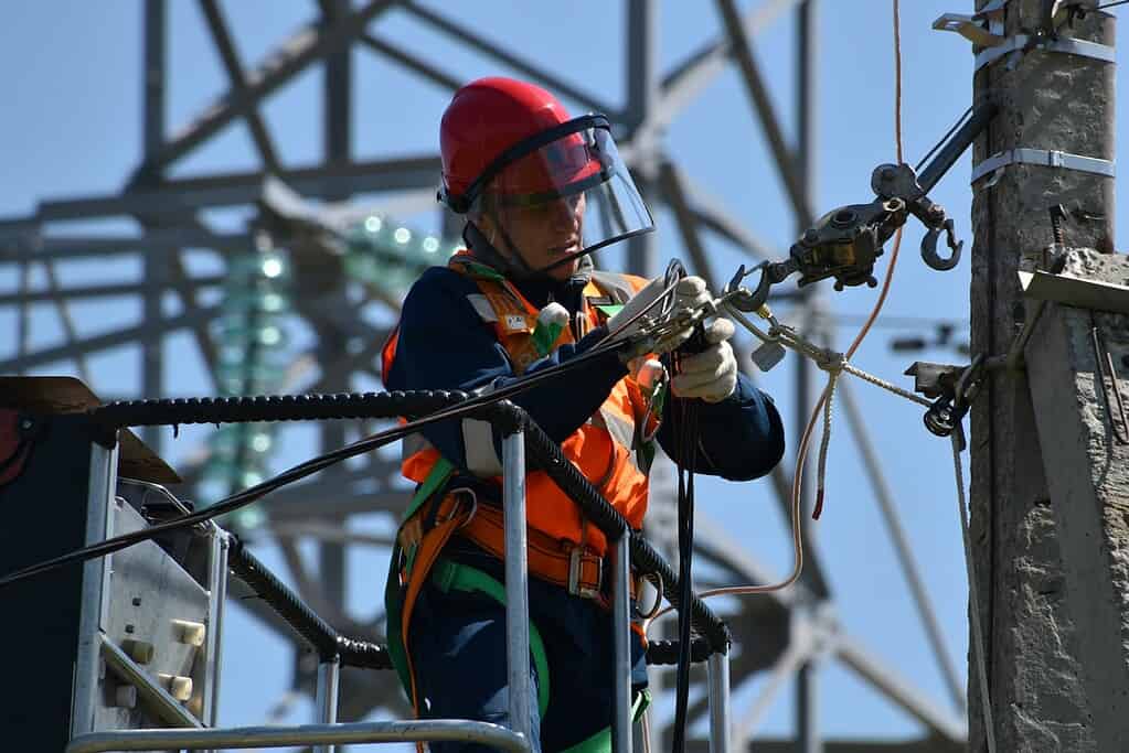 shallow focus photo of man fixing steel cable